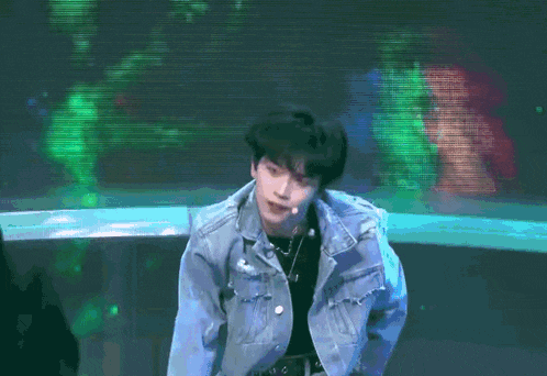 a man in a denim jacket is standing on a stage