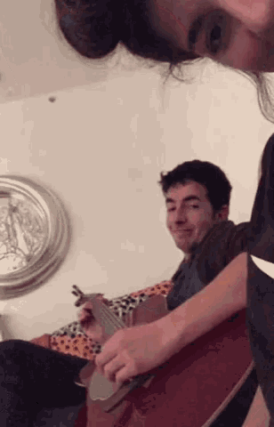 a man is playing a guitar while a woman watches