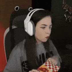 a girl wearing headphones is sitting in a chair and eating a bag of food .