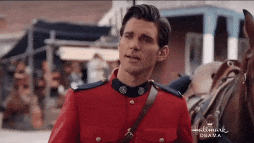 a man in a red uniform is standing next to a horse in a hallmark drama scene