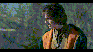 a man wearing an orange vest and a blue jacket looks to the side