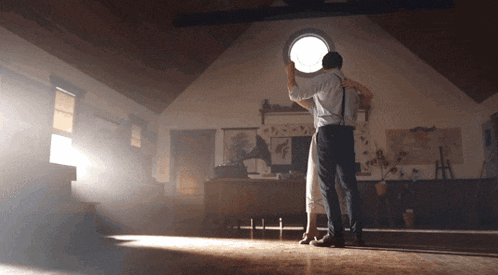 a man and a woman are dancing in a room with a round window