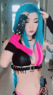 a woman with blue hair is wearing a pink and black costume with bullets on it .