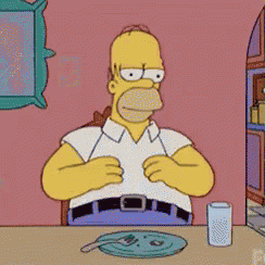 homer simpson sits at a table with a plate and a glass of water