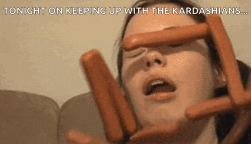 a woman is holding a bunch of hot dogs in front of her face