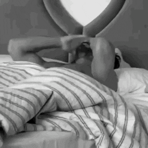 a black and white photo of a man laying in a bed with his arms outstretched .
