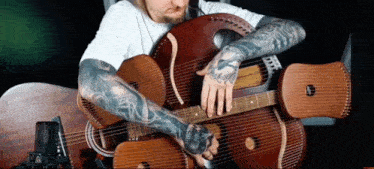 a man with tattoos on his arms is holding a guitar and a harp