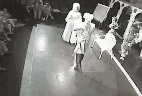 a black and white photo of two people dancing on a stage in front of a crowd .