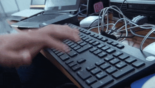a person is typing on a keyboard with a sticker on the wall that says ' i love you '