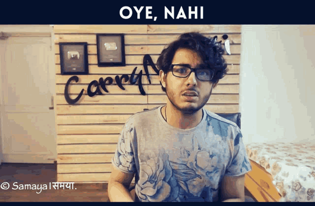 a man wearing glasses is standing in front of a wall that says " carry "