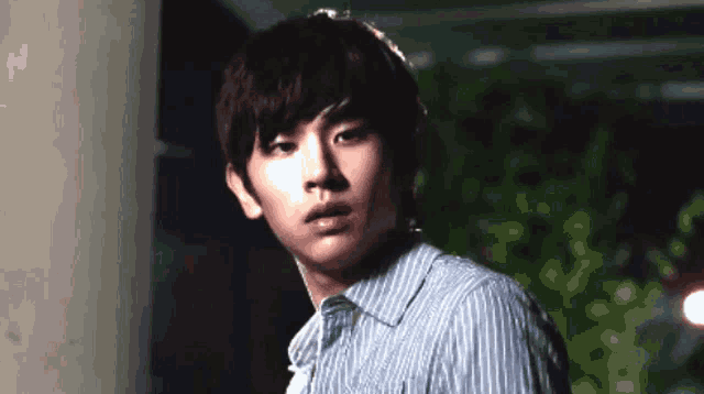 a young man in a striped shirt looks to the side
