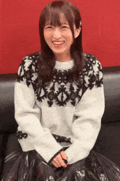 a woman wearing a white and black sweater is smiling
