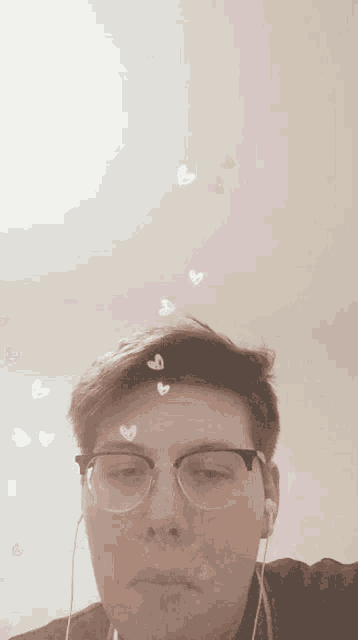 a man wearing glasses and ear buds looks at the camera