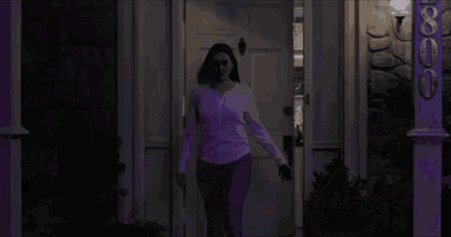 a woman in a purple sweater is standing in front of a white door .