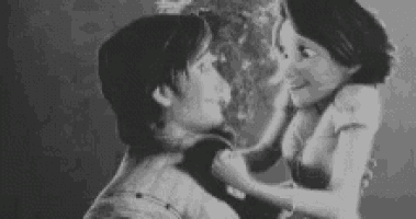 a black and white photo of a man and a woman kissing each other .