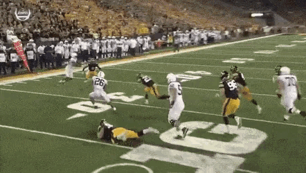 a group of football players are playing a game on a field . one of the players has the number 26 on his jersey .