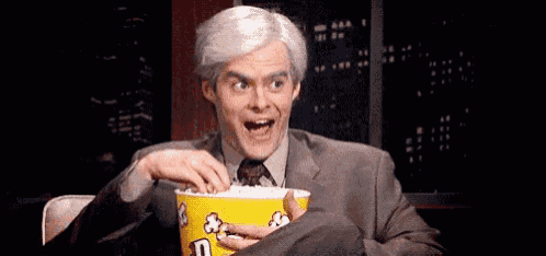 a man in a suit and tie is eating popcorn .