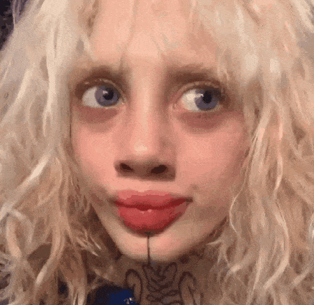 a close up of a woman 's face with blonde hair and red lips