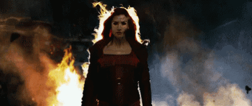 a woman in a red jacket is standing in front of a large fire .