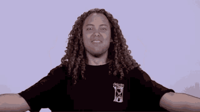 a man with long curly hair wearing a black shirt that says delayoo