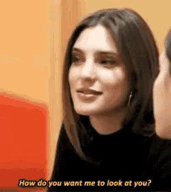 a woman is talking to a man and asking him to look at her .