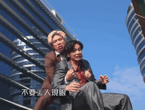 a man in a suit is holding another man in a chair with chinese writing on the bottom