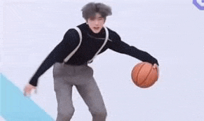 a man is holding a basketball in his hands while standing on a white surface .
