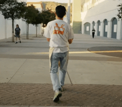 a man walking down a sidewalk wearing a t-shirt with a picture of a rabbit on it