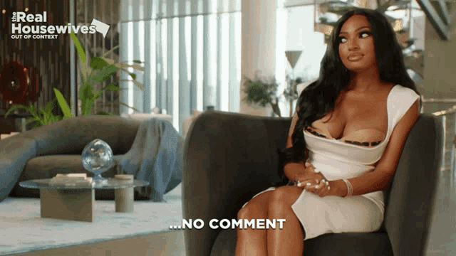 a woman in a white dress is sitting in a chair with her legs crossed and says no comment