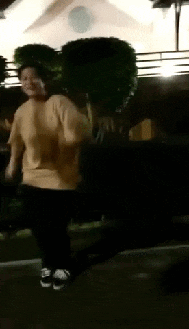 a woman in a yellow shirt is dancing in front of a building at night .