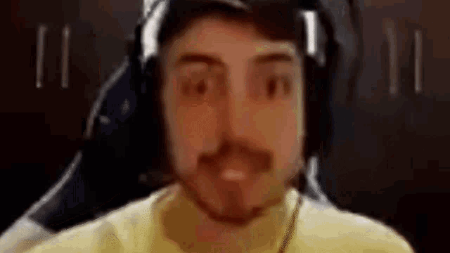 a man with a beard wearing headphones and a yellow shirt .