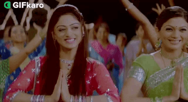 a group of women are dancing together and one of them is wearing a pink dress .