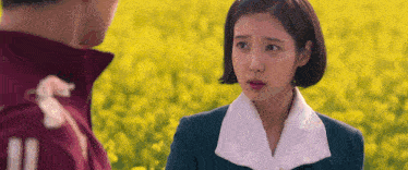 a man and a woman are standing next to each other in a field of yellow flowers .