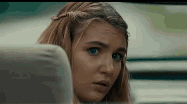 a young woman with blue eyes is sitting in the back seat of a car .