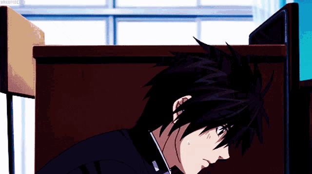 a black haired anime character is sitting at a desk in front of a computer monitor