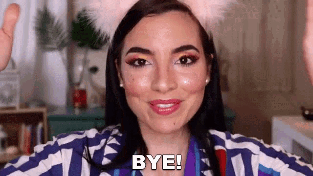 a woman wearing a cat ears headband is waving her hand and saying bye .
