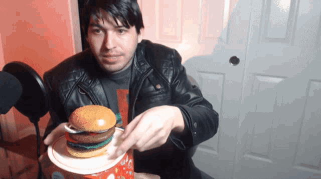 a man in a leather jacket is eating a hamburger