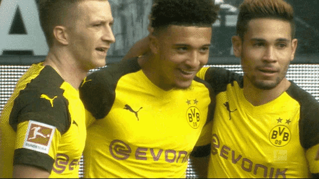 three soccer players wearing yellow shirts with bvb on the front