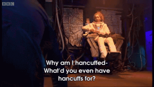 a bbc screen shows a man in a space suit talking to a woman in a chair