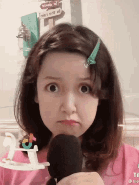 a girl in a pink shirt is holding a microphone