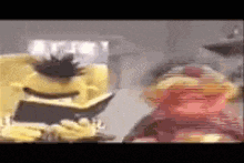 two sesame street characters are sitting next to each other in a living room .