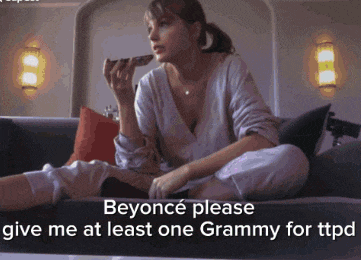 a woman is sitting on a couch holding a remote control and asking beyonce please give me at least one grammy