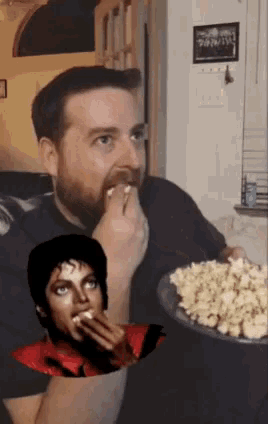 a man with a beard is eating popcorn with a picture of michael jackson behind him