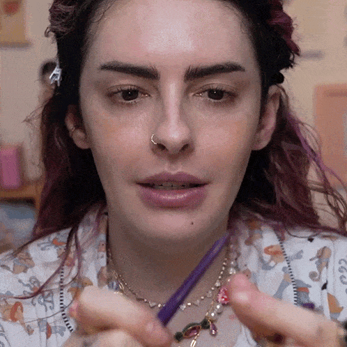 a woman with purple hair and a nose ring is holding a purple pencil
