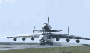a large airplane is taking off from a runway with a space shuttle on top of it
