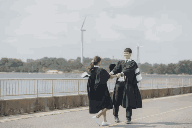 a man and woman in graduation gowns holding hands