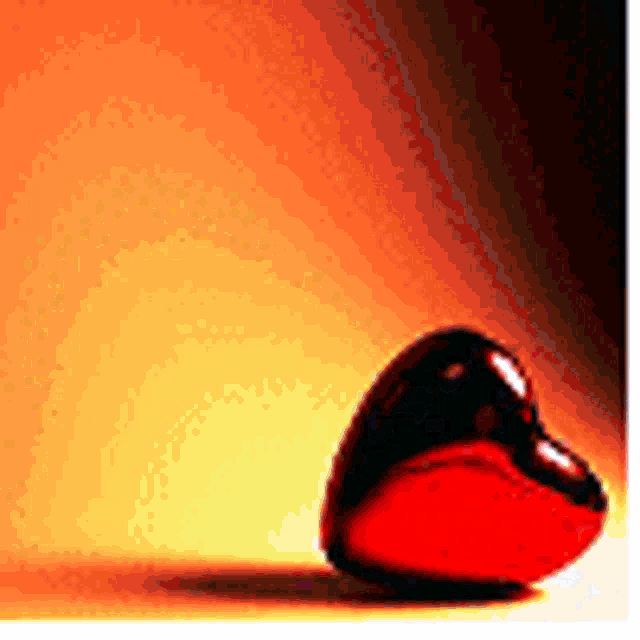a red heart is sitting on a table with a yellow background .