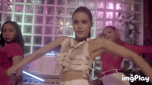 a woman in a white top is dancing in front of a group of girls .