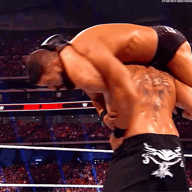 a wrestler is carrying another wrestler on his shoulders with the hashtag #thenextthing