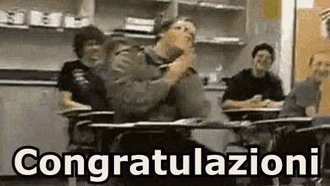 a group of people are sitting at desks in a classroom with the words congratulations written on the bottom .